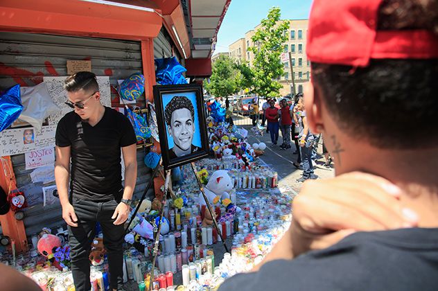 Celebrity artist Samil Alva, left, steps over candles after placing a portrait he painted of 15-year-old Lesandro Guzman-Feliz at a community memorial in New York earlier this week